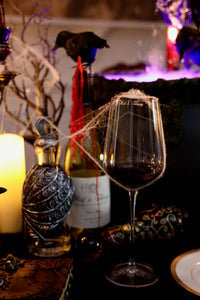 Wine glass with red wine, bottle, and decorative elements on a dark surface.